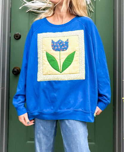 A woman wearing a blue sweatshirt with a flower on it.