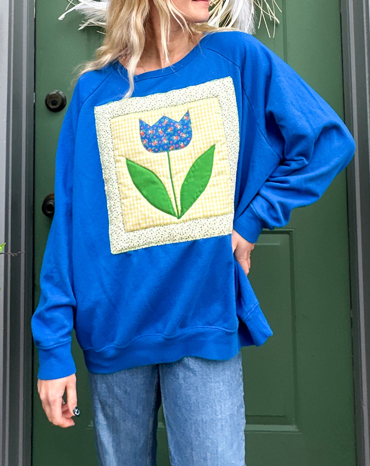 A woman wearing a blue sweatshirt with a flower on it.
