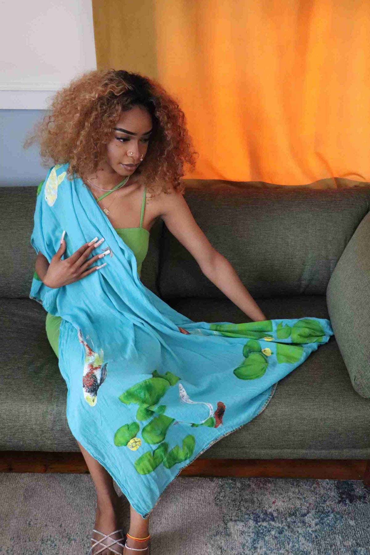 a woman sitting on a couch in a blue dress.