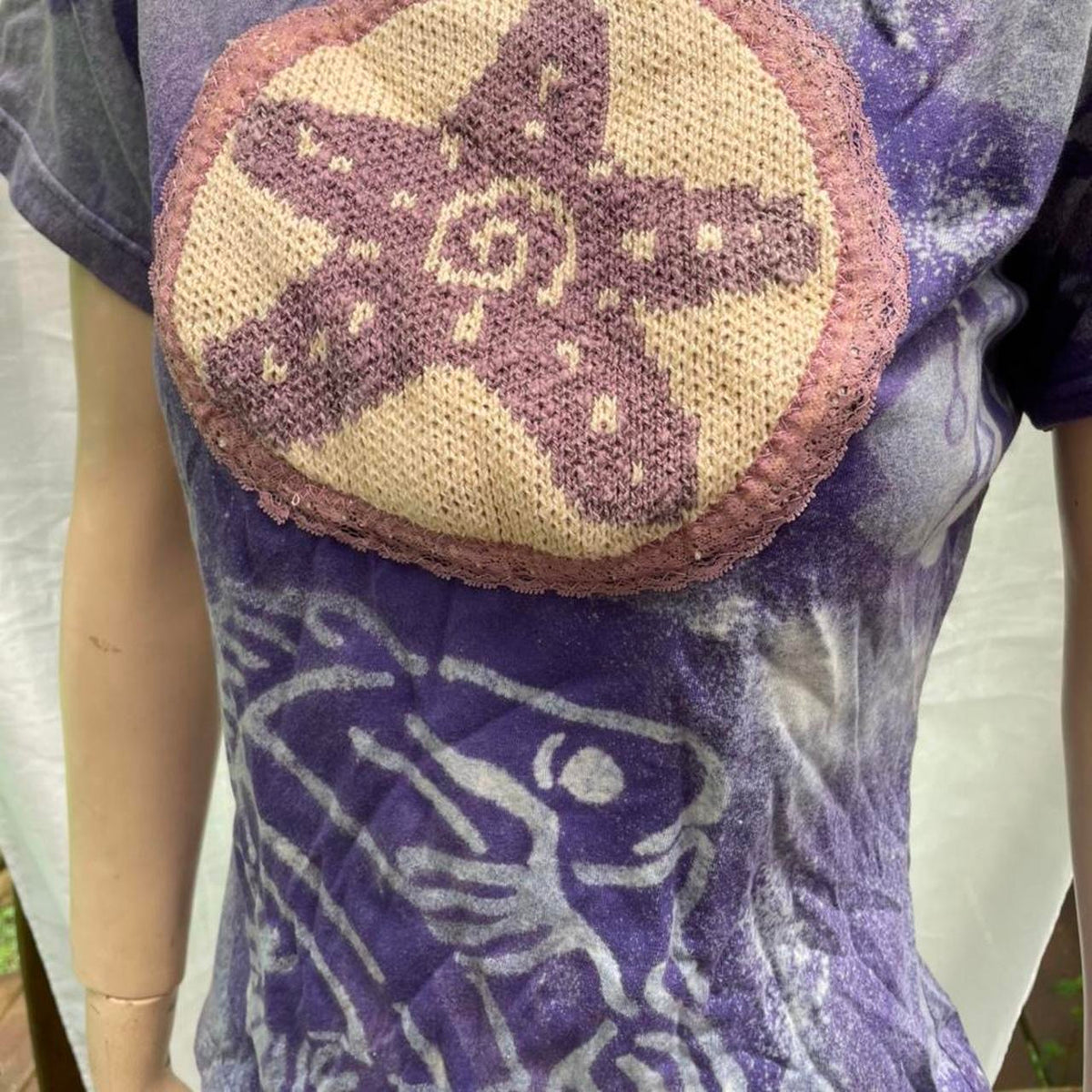 A mannequin wearing a purple t - shirt with a starfish on it.
