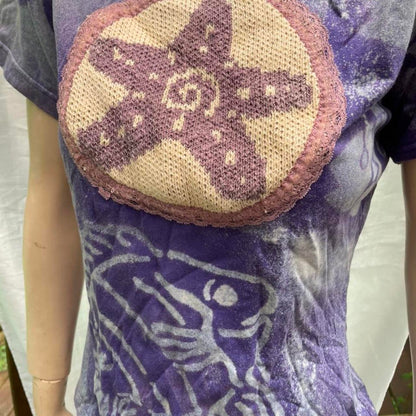 A mannequin wearing a purple t - shirt with a starfish on it.