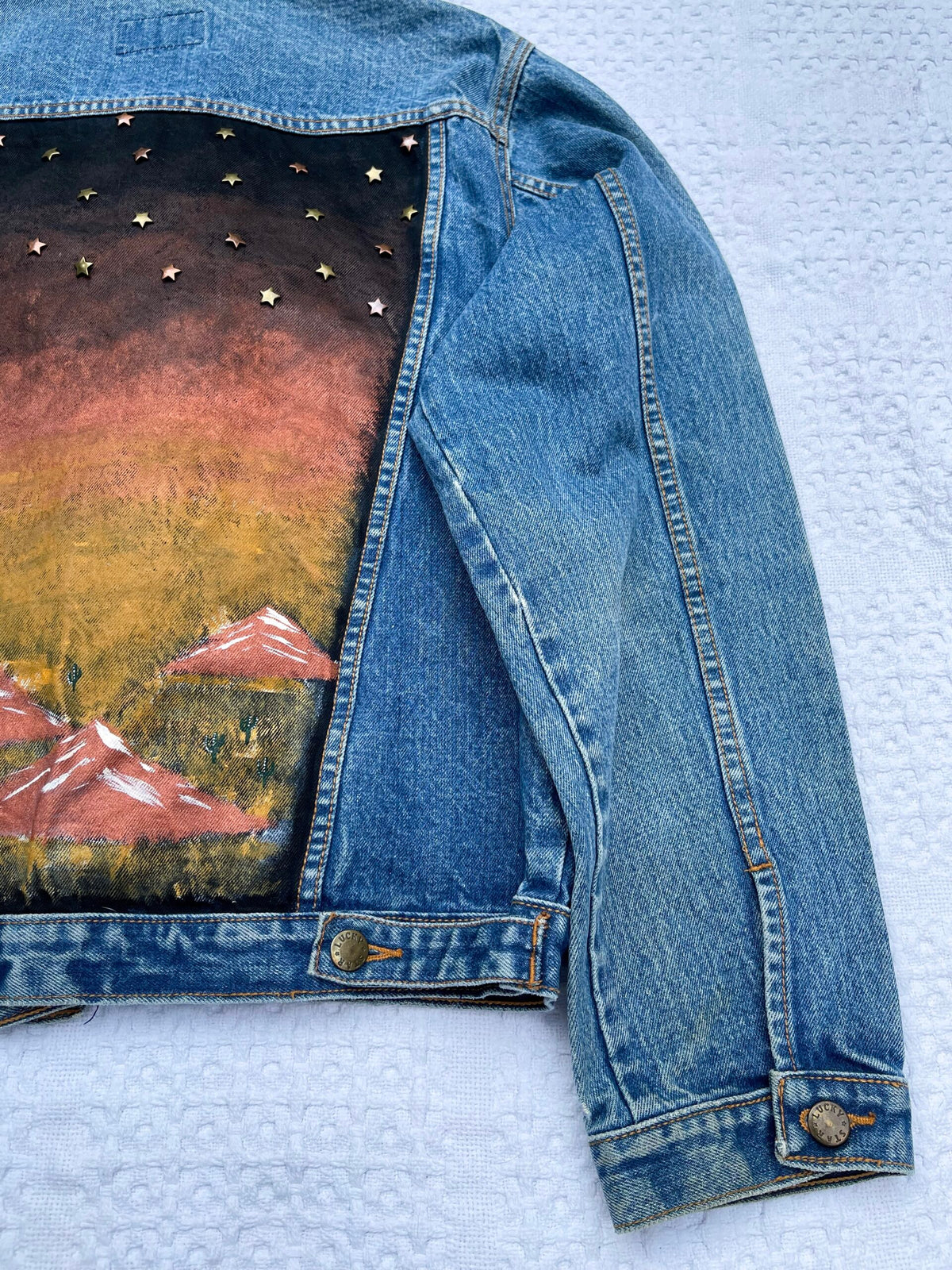 A denim jacket with mountains painted on it.