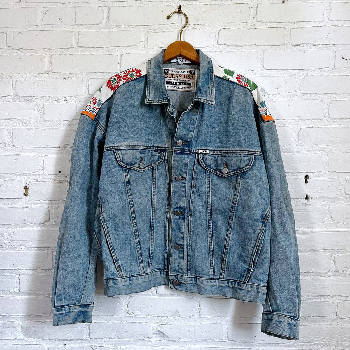 A denim jacket hanging on a brick wall.