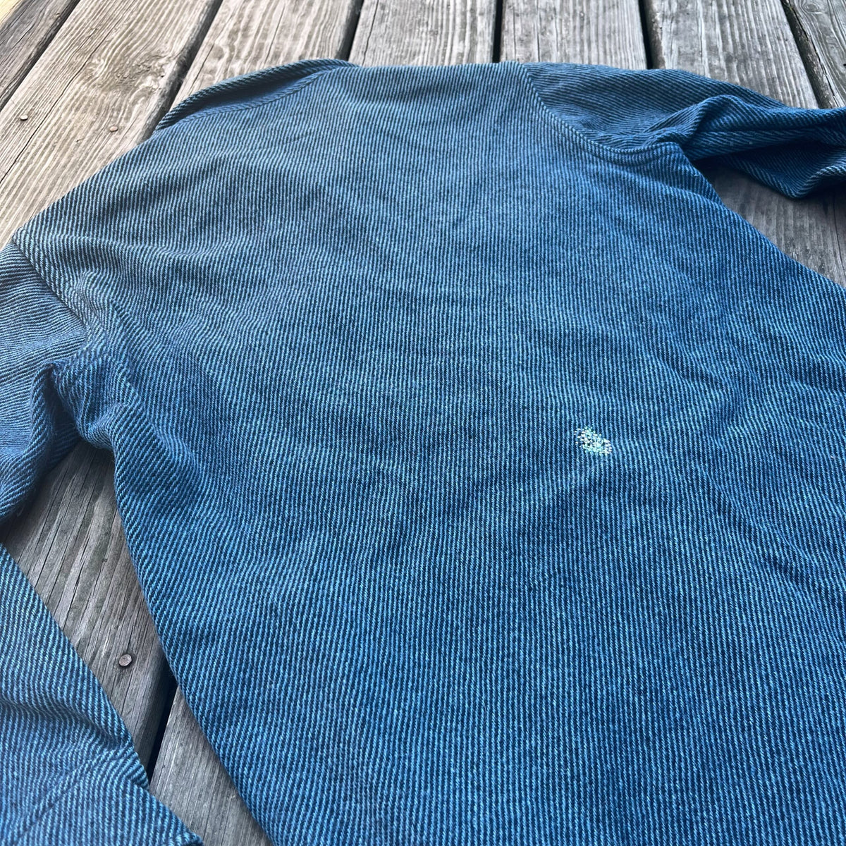 A blue wool shirt on a wooden deck.