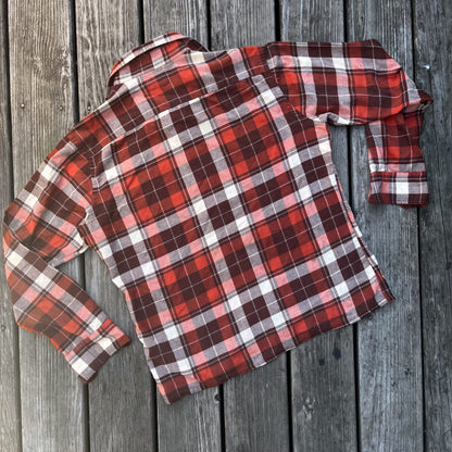 An orange and white plaid shirt on a wooden floor.