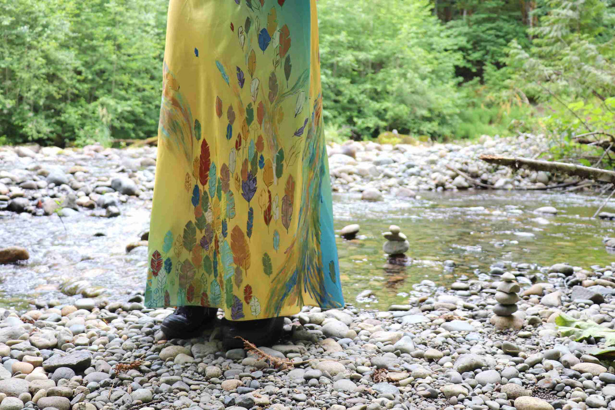 a woman standing on a rock covered river bank.
