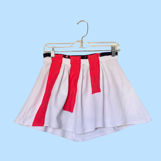 A white and red skirt hanging on a hanger.