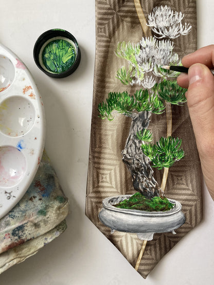 A person is painting a picture of a hand-painted bonsai tree and dragonflies silk tie.