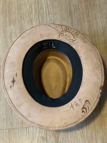 A suede hat wood burned with accessories sitting on a table.