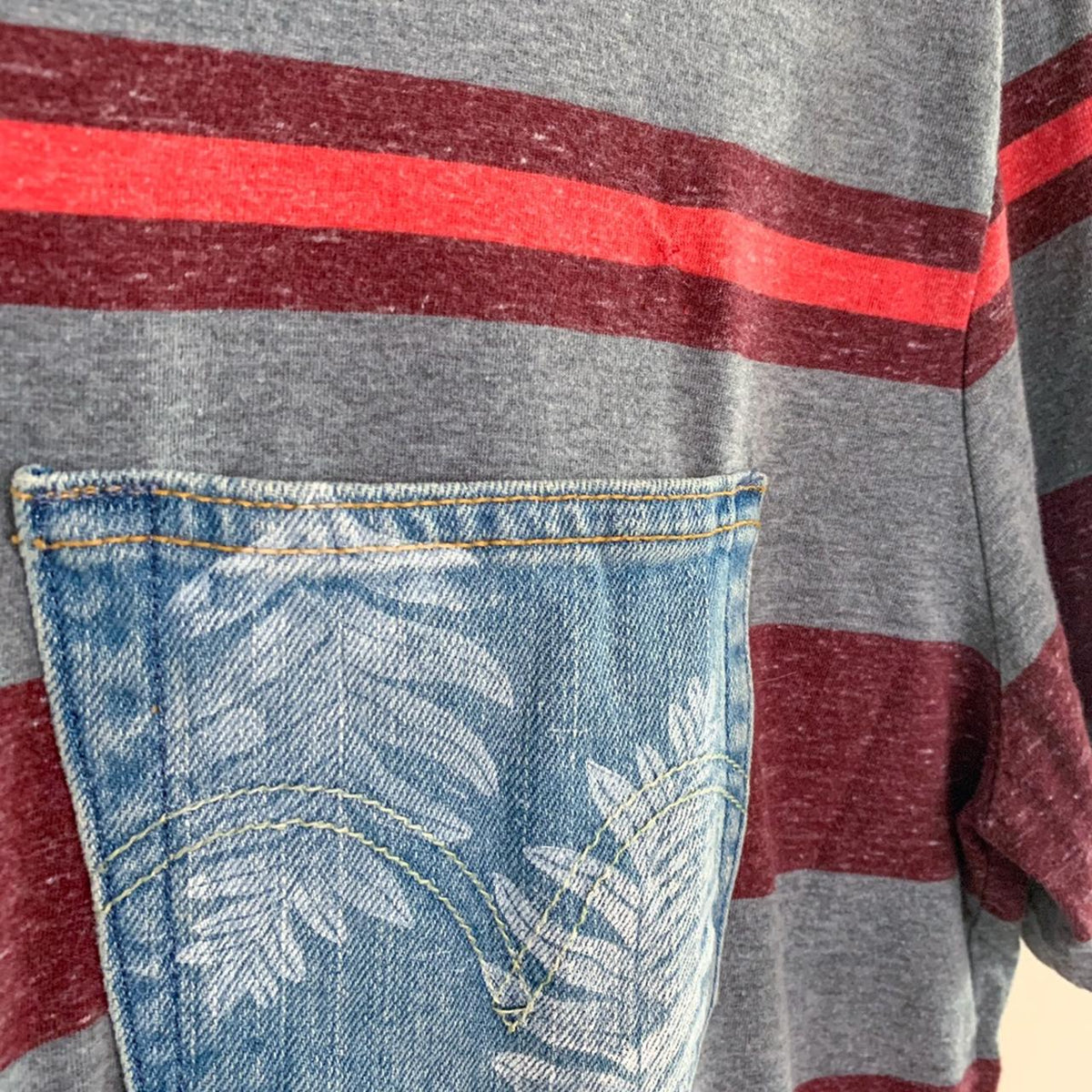 A striped t - shirt with a palm leaf on the pocket.