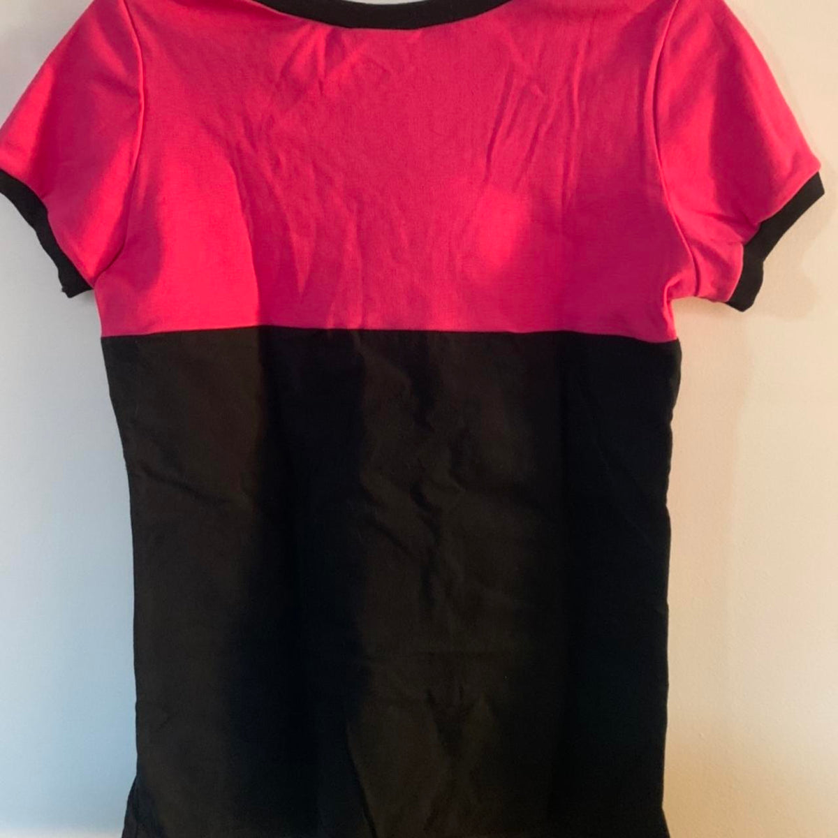 A pink and black t - shirt hanging on a hanger.