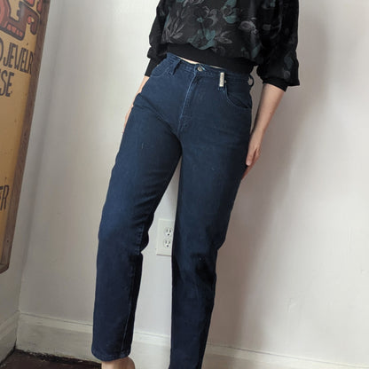 A woman standing next to a wall with her hands in the pockets of her Reworked Embroidered Rainbow Star Pocket Jeans.