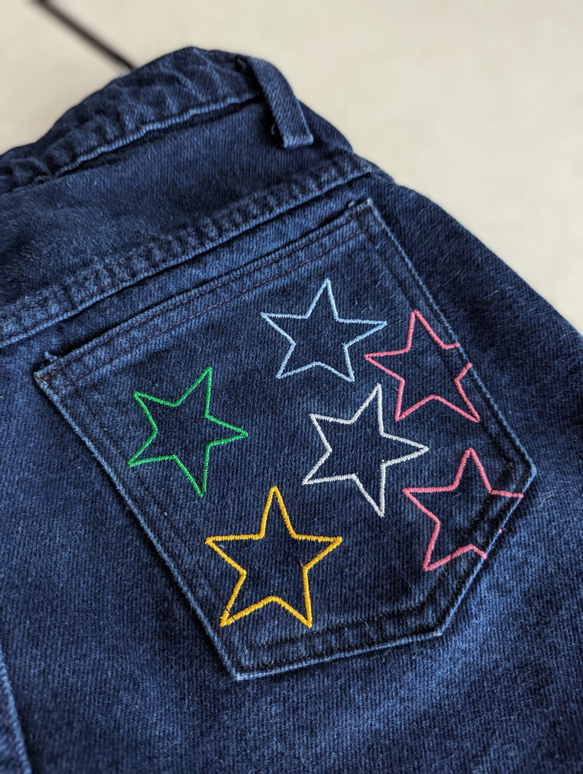A pair of Reworked Embroidered Rainbow Star Pocket Jeans.