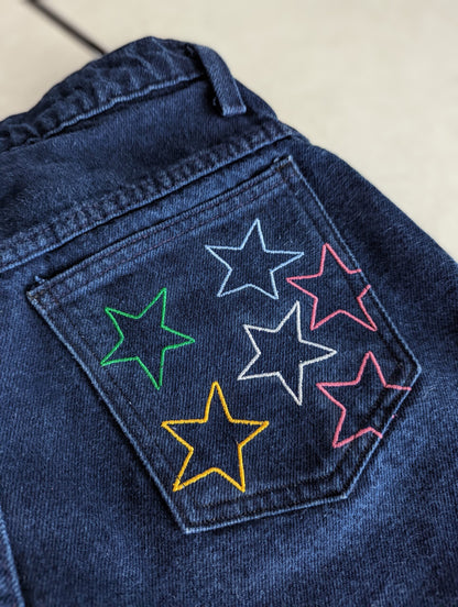 A pair of Reworked Embroidered Rainbow Star Pocket Jeans.