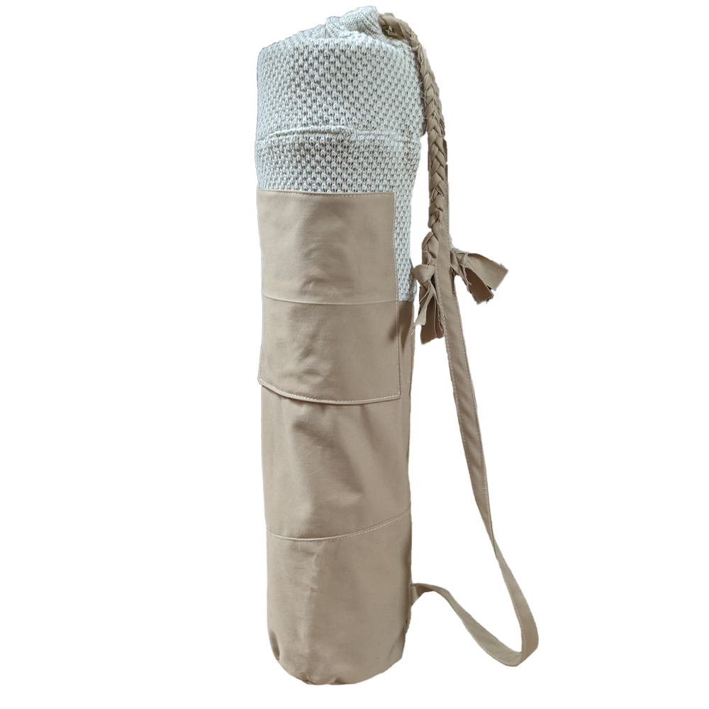 A beige yoga mat with a strap on it.