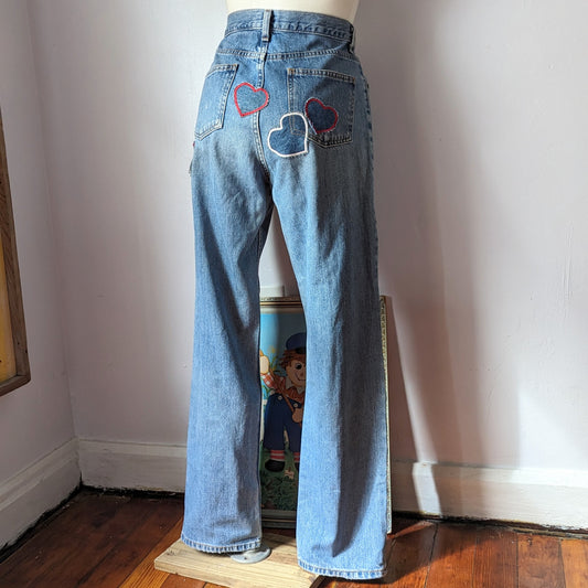 A mannequin wearing a pair of jeans with embroidered hearts.
