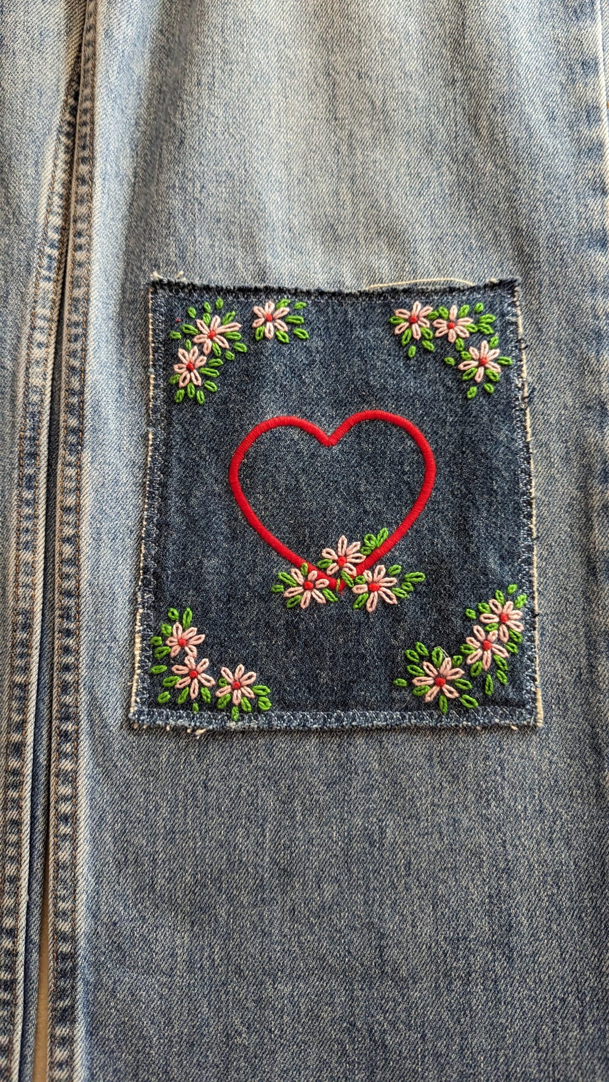 A denim jacket with a heart embroidered on it.