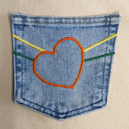 A heart embroidered on a blue denim pocket.
