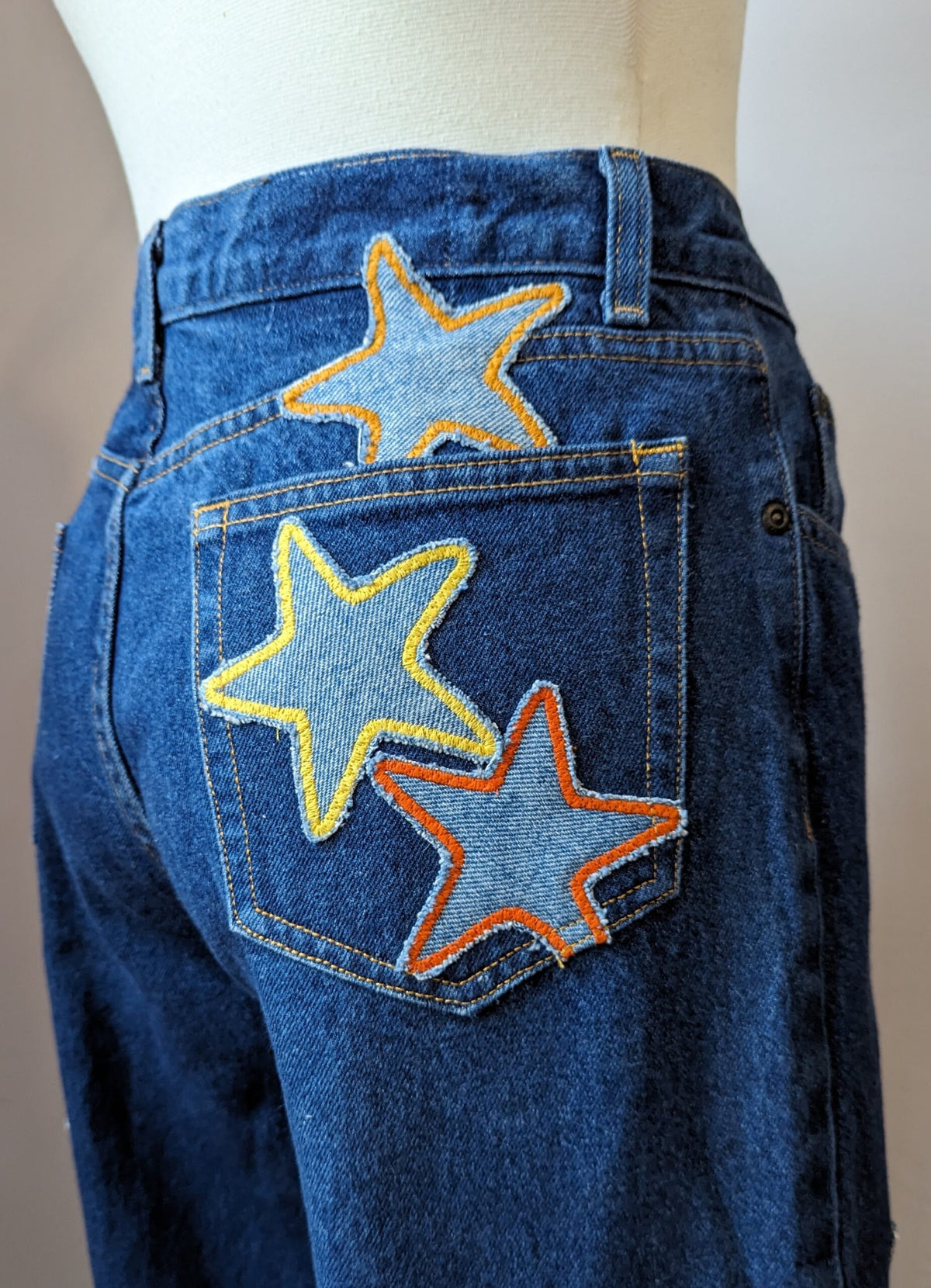 A pair of blue jeans with stars embroidered on them.