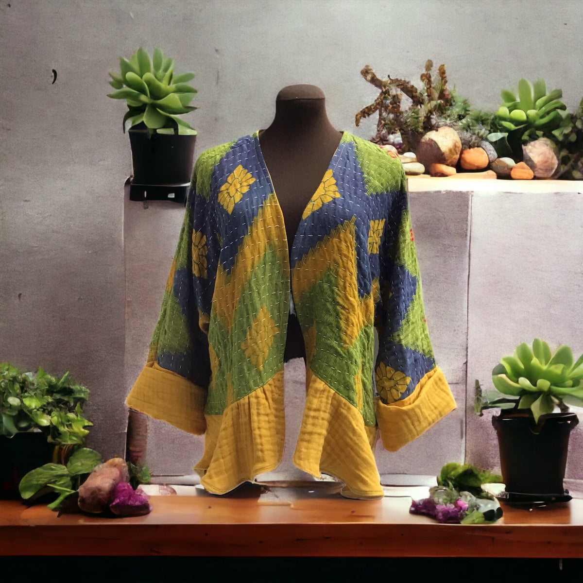 A mannequin is sitting on a table next to plants.