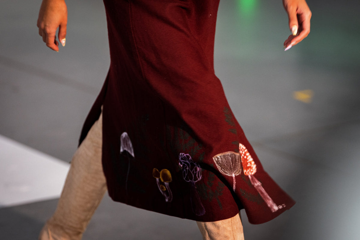 Bottom of maroon skirt with painted mushrooms and ferns on it