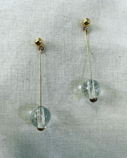 a pair of earrings on a white cloth.