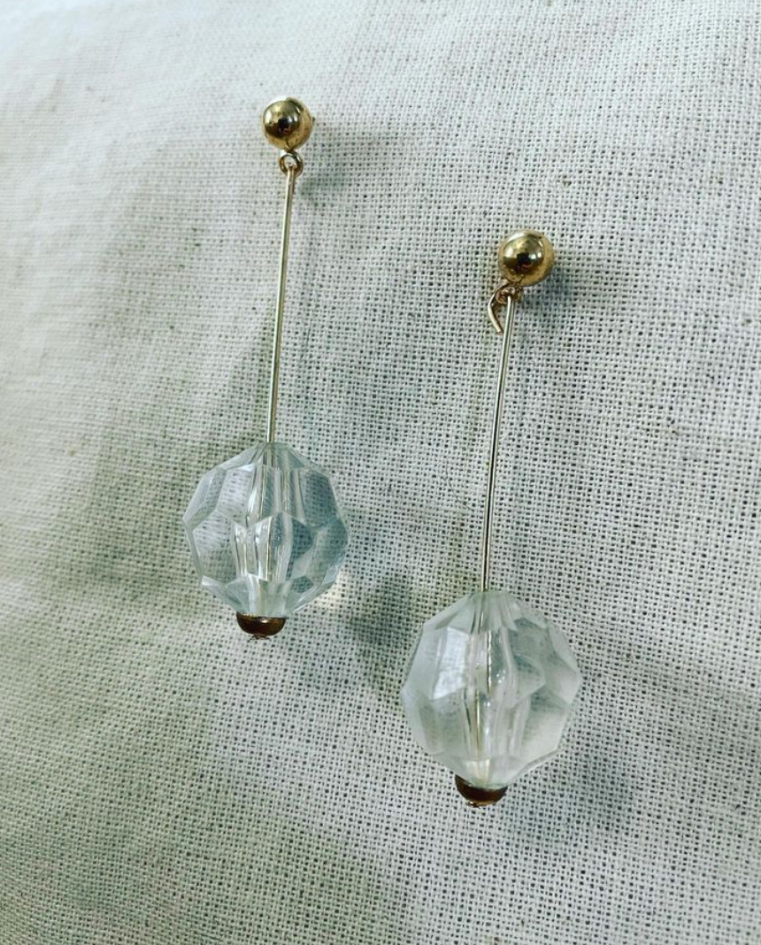 a pair of earrings sitting on top of a white cloth.