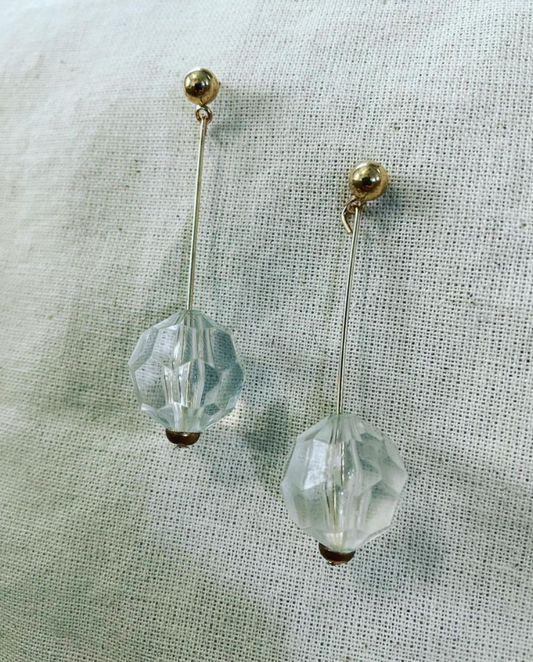 a pair of earrings sitting on top of a white cloth.