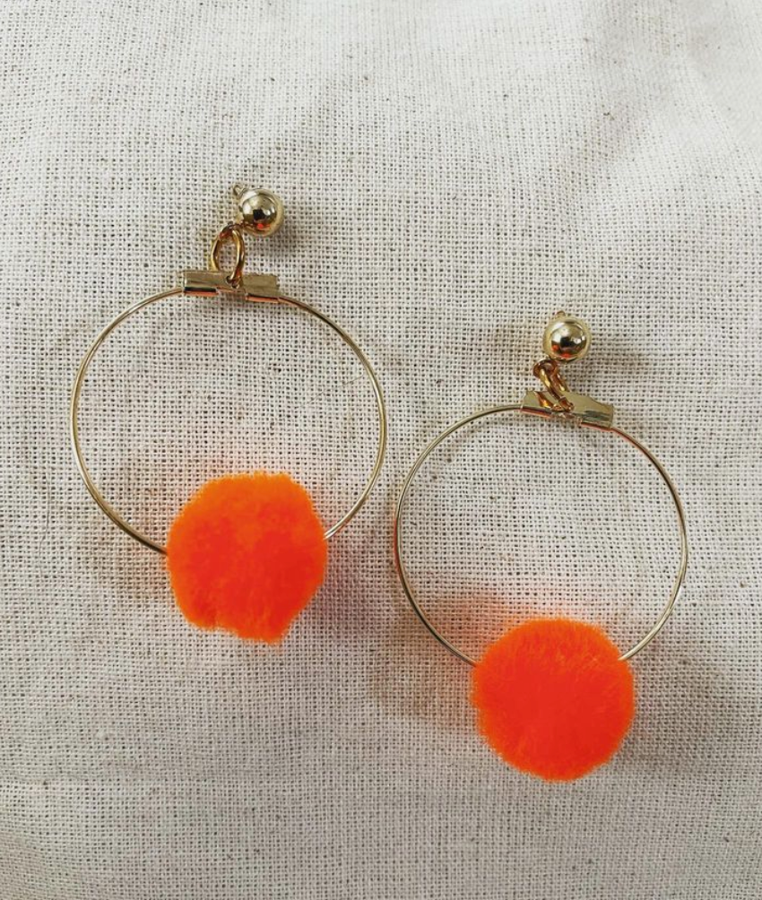 a pair of orange earrings on a white cloth.