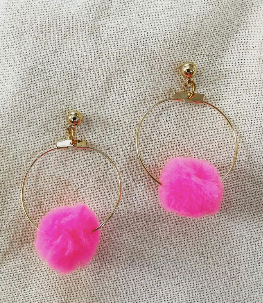 a pair of hoop earrings with pink pom pom.