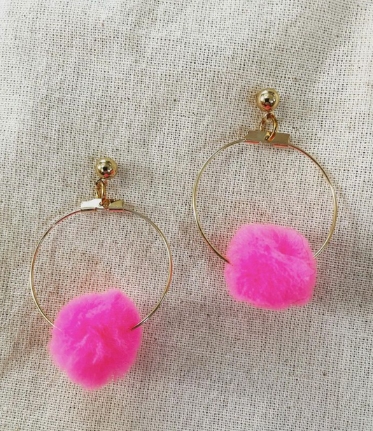 a pair of hoop earrings with pink pom pom.