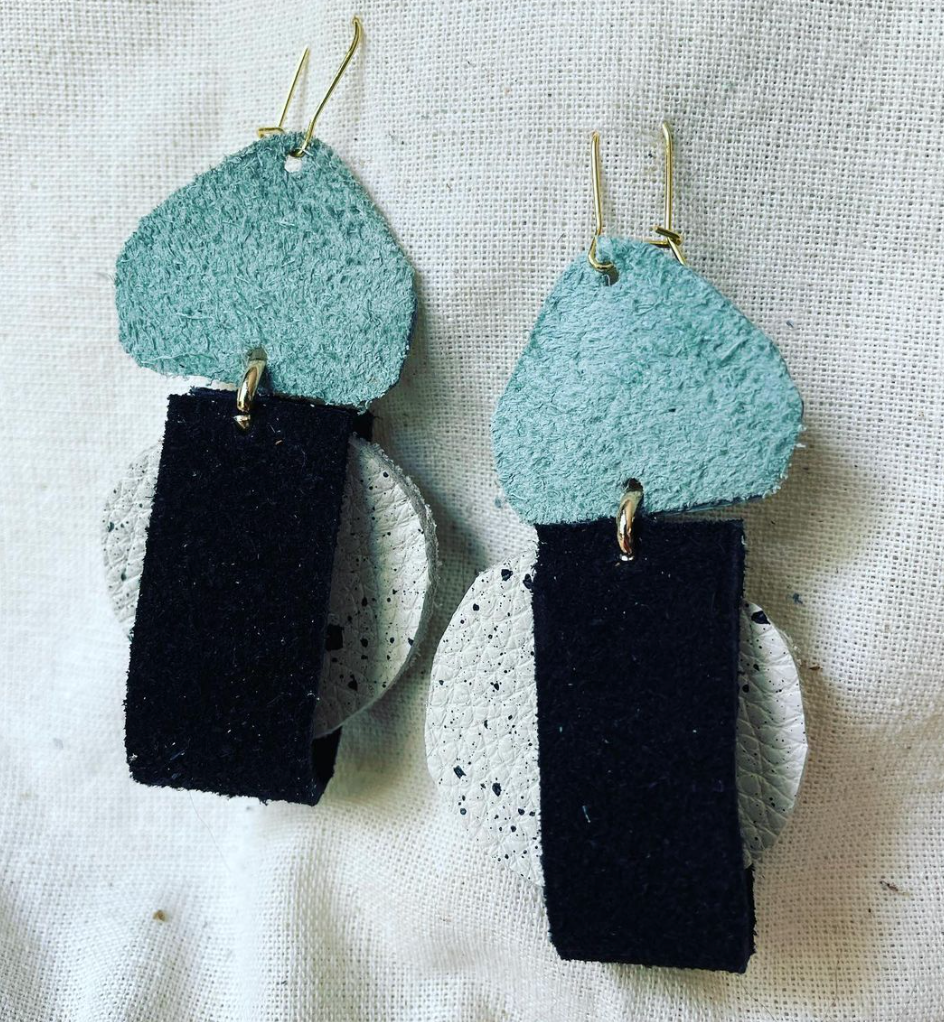 a pair of black and blue earrings on a white surface.