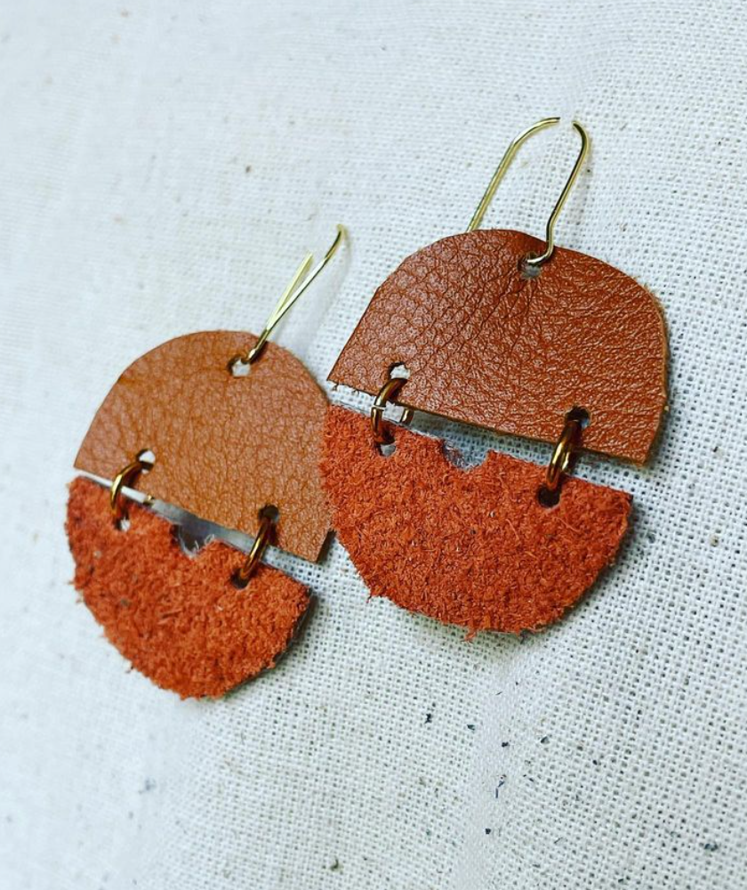 a pair of brown and tan leather earrings.