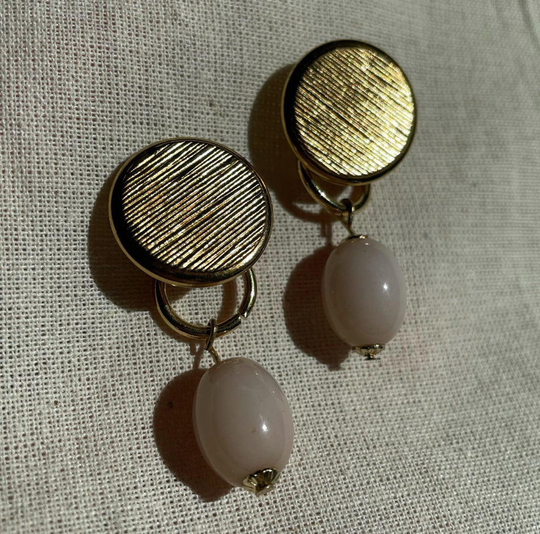 a pair of earrings sitting on top of a white cloth.