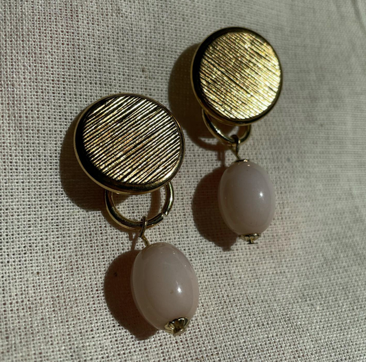 a pair of earrings sitting on top of a white cloth.