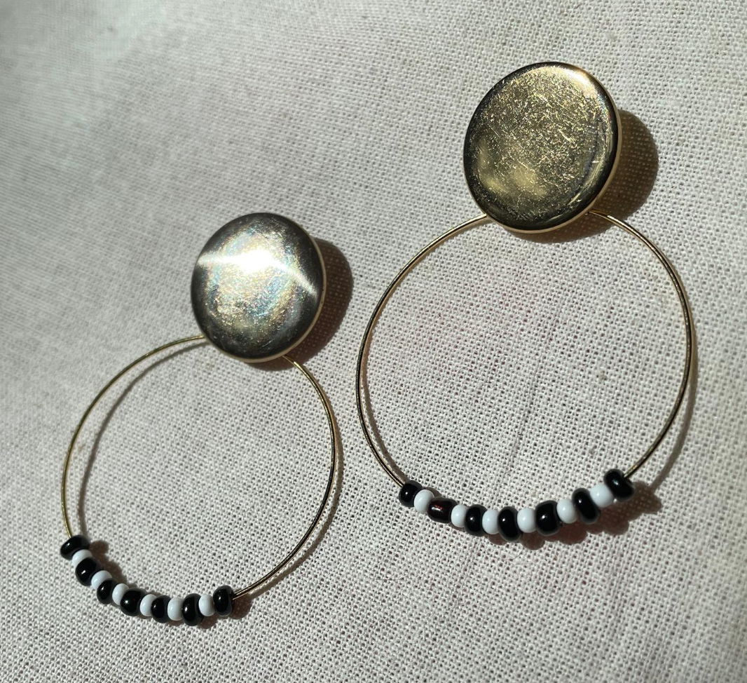 a pair of black and white beaded hoop earrings.