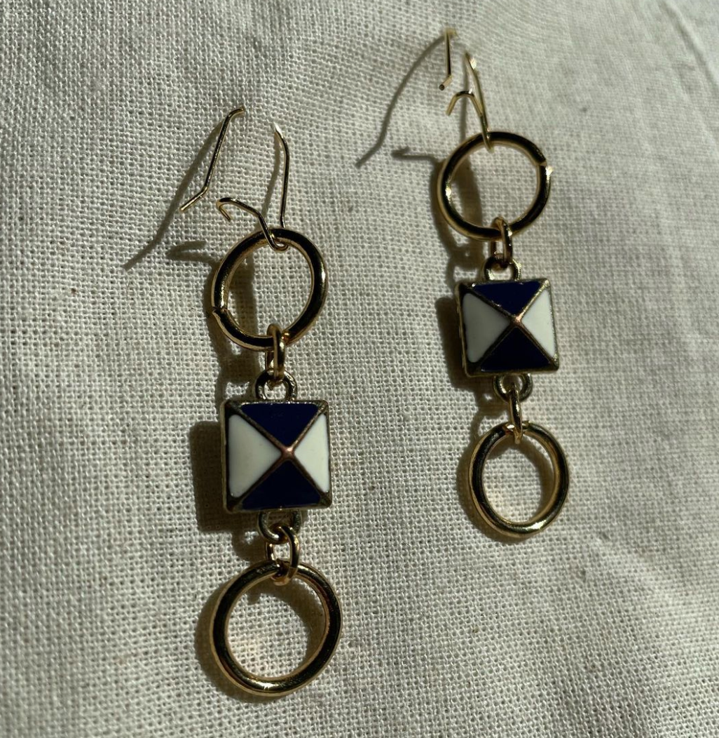 a pair of earrings sitting on top of a white cloth.