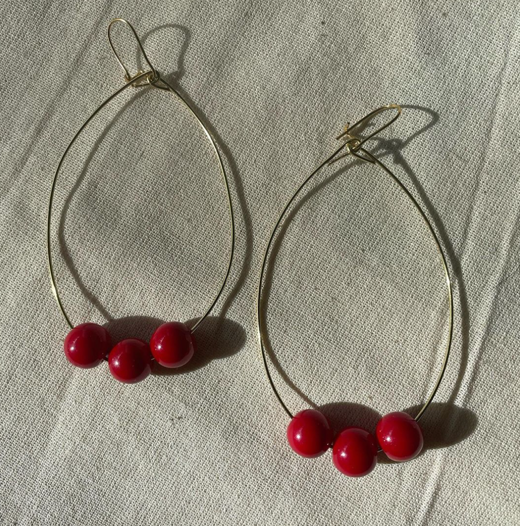 a pair of hoop earrings with red beads.
