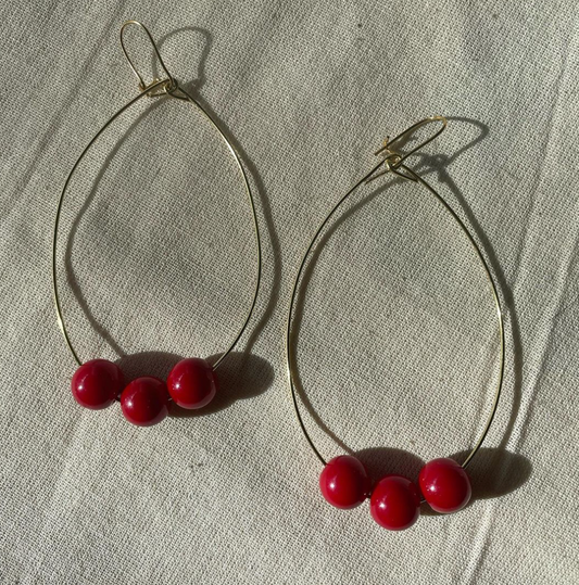 a pair of hoop earrings with red beads.