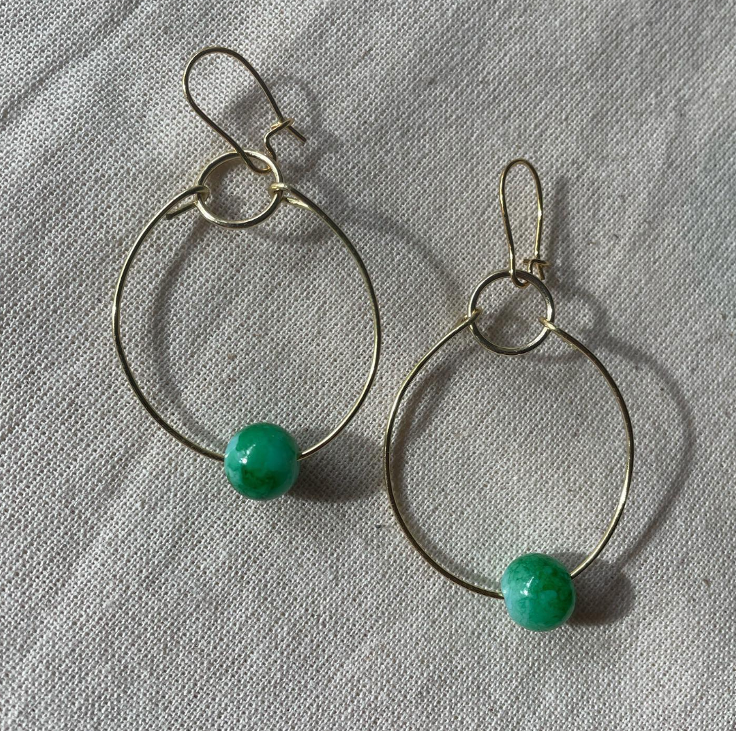 a pair of hoop earrings with green beads.