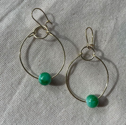 a pair of hoop earrings with green beads.