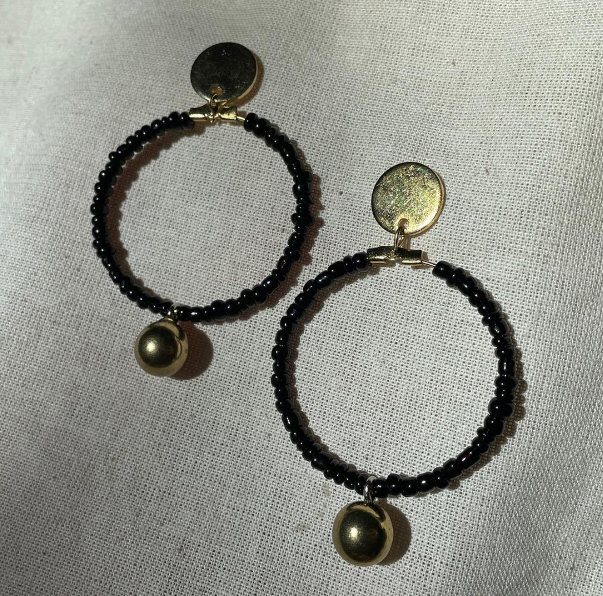 A pair of Black beaded gold drop hoop earrings.