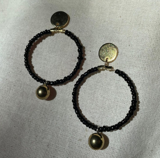 A pair of Black beaded gold drop hoop earrings.