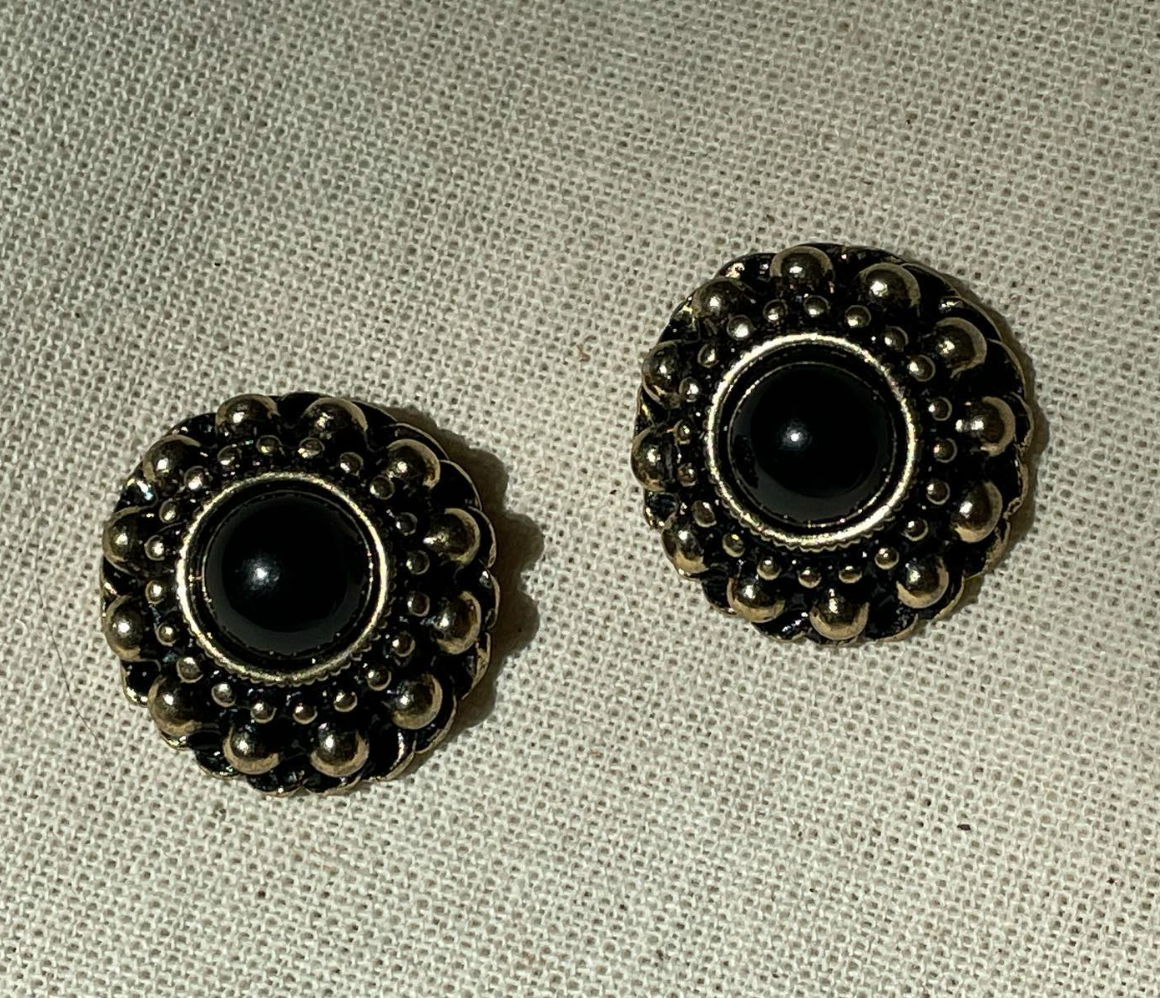 a pair of black and silver buttons on a white cloth.