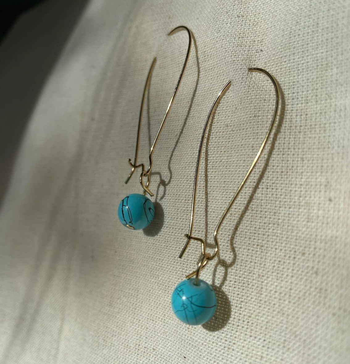 a pair of earrings sitting on top of a white cloth.