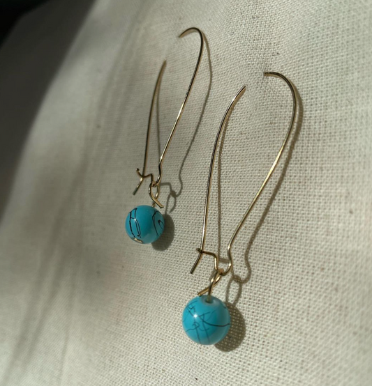 a pair of earrings sitting on top of a white cloth.