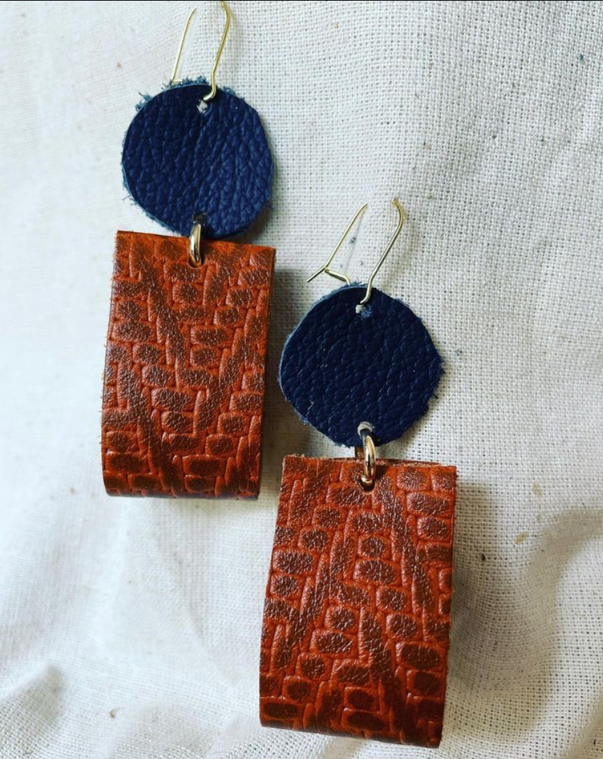 a pair of brown and blue earrings on a white surface.