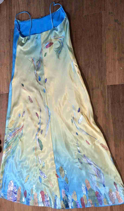 a dress laying on a wooden floor next to a pair of scissors.