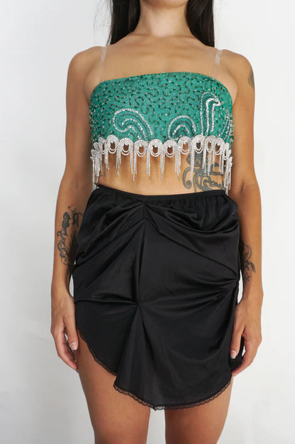 A woman wearing a LACE ICING Black Mini Skirt and a green top.