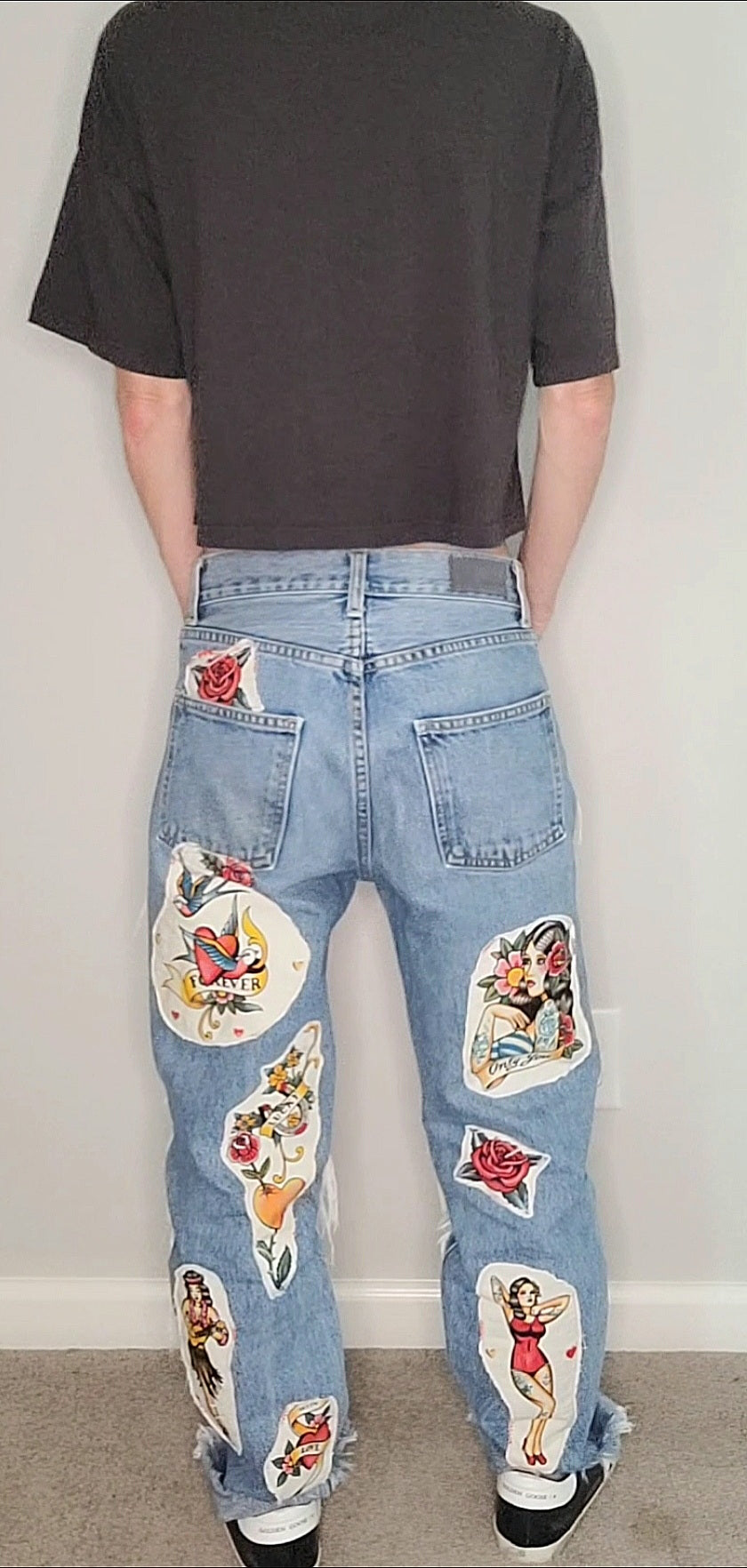a man wearing a pair of jeans with a lot of stickers on them.